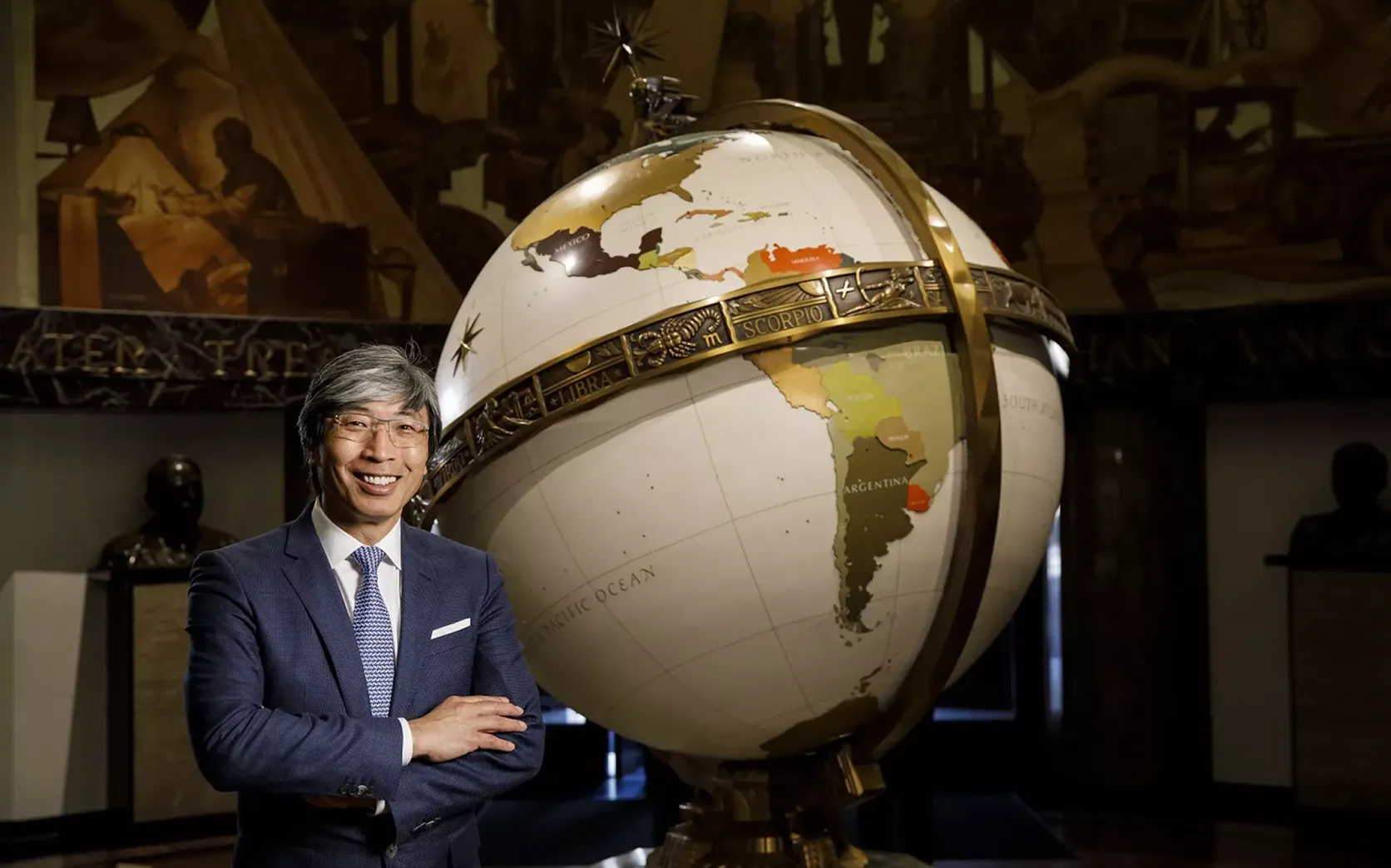 A man standing in front of a large globe.